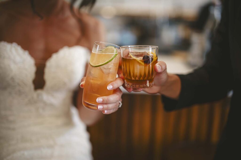 A bride and groom toasting drinks at a bar.
